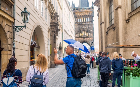 Tour guide leading group near Charles Bridge in Prague.