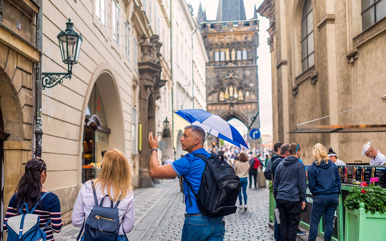 Tour guide leading group near Charles Bridge in Prague.