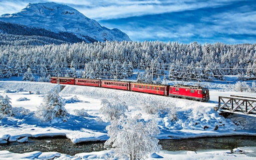 Bernina Express train traveling through snowy Swiss Alps landscape.