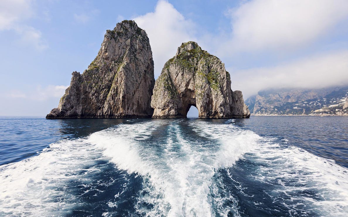 Boat approaching Faraglioni rock formations on Capri, Italy during a day trip from Naples.