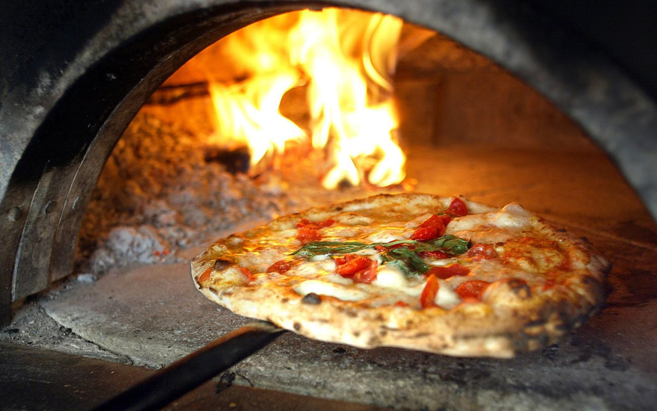 Pizza baking in a wood-fired oven during a cooking class in Naples.