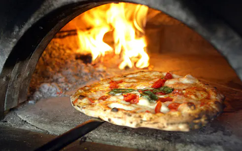 Pizza baking in a wood-fired oven during a cooking class in Naples.