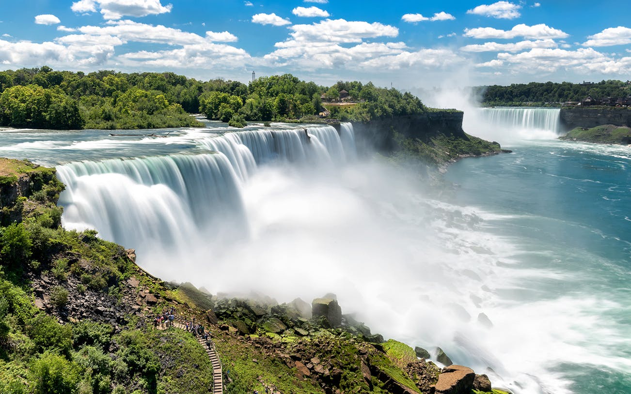 Niagara Falls with mist and tourists on viewing platform, seen on a day trip from New York City.