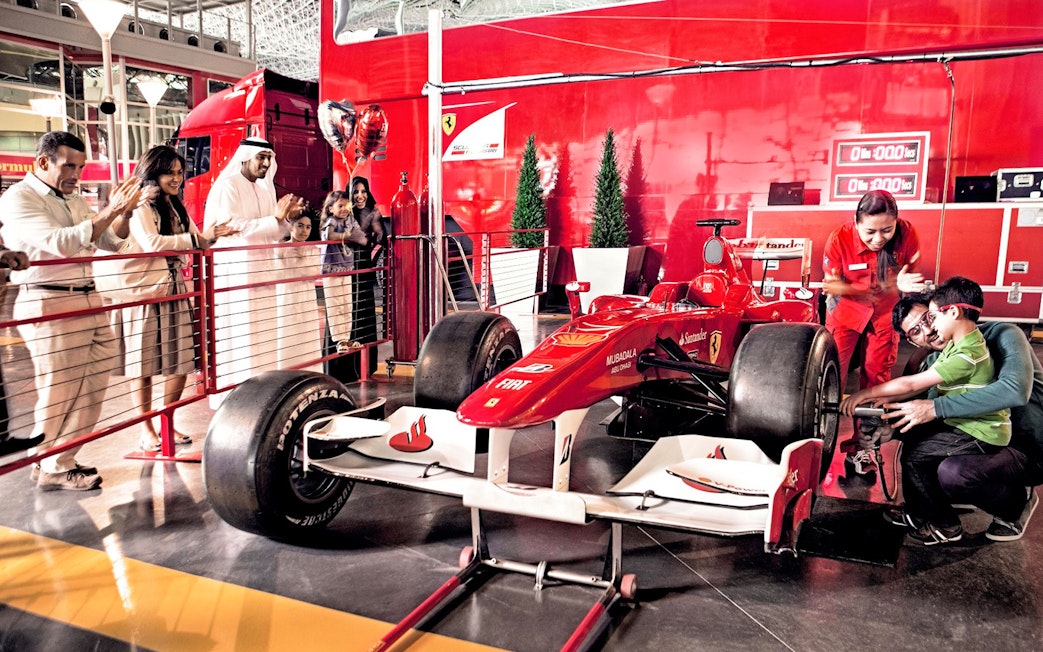 Visitors at Ferrari World Abu Dhabi interacting with a Formula 1 car exhibit.