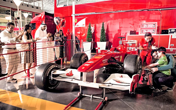 Visitors at Ferrari World Abu Dhabi interacting with a Formula 1 car exhibit.