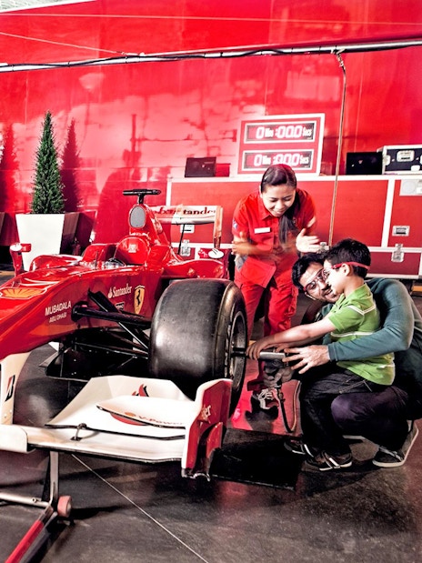 Visitors at Ferrari World Abu Dhabi interacting with a Formula 1 car exhibit.