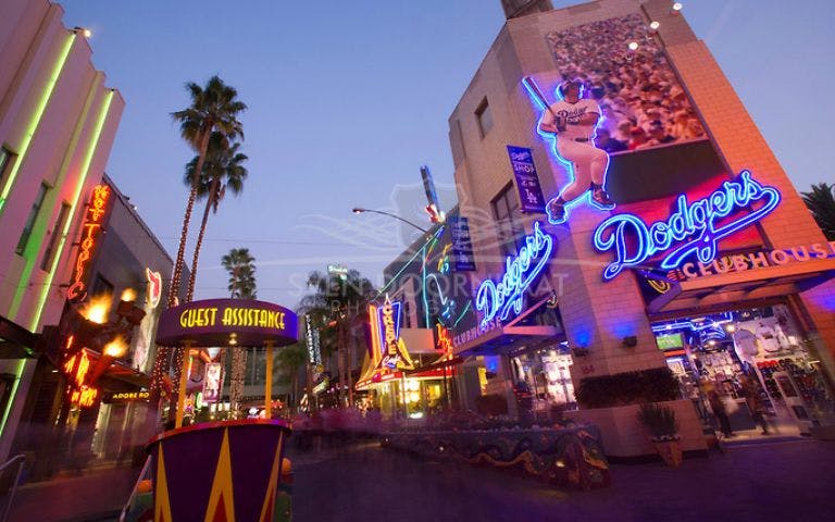 Universal Studios Hollywood neon signs and guest assistance booth at dusk.