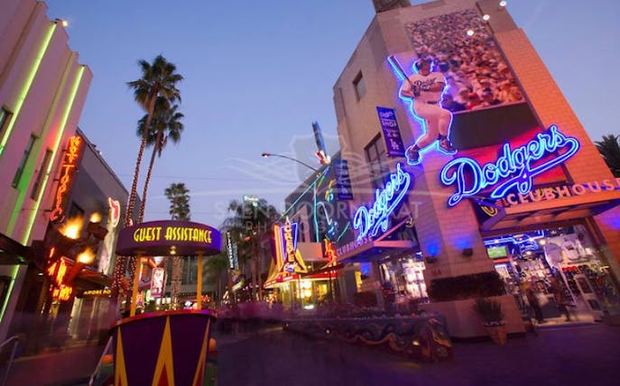 Universal Studios Hollywood neon signs and guest assistance booth at dusk.