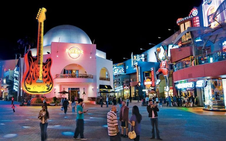 Universal Studios Hollywood CityWalk at night with neon signs and visitors.