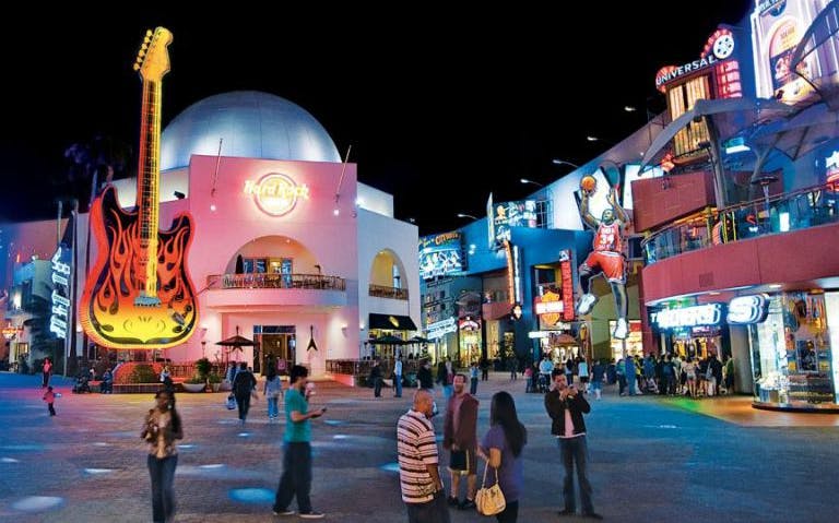 Universal Studios Hollywood CityWalk at night with neon signs and visitors.