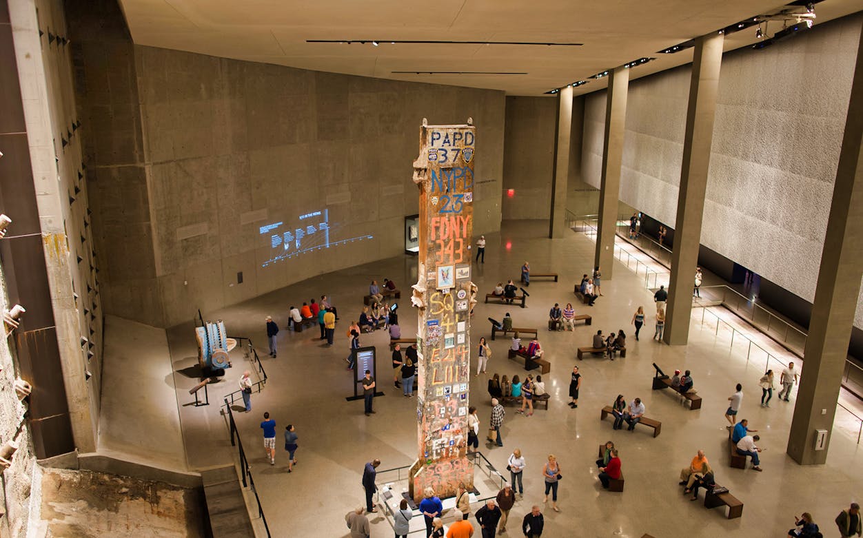 Visitors at 9/11 Tribute Museum viewing memorial artifacts and exhibits.
