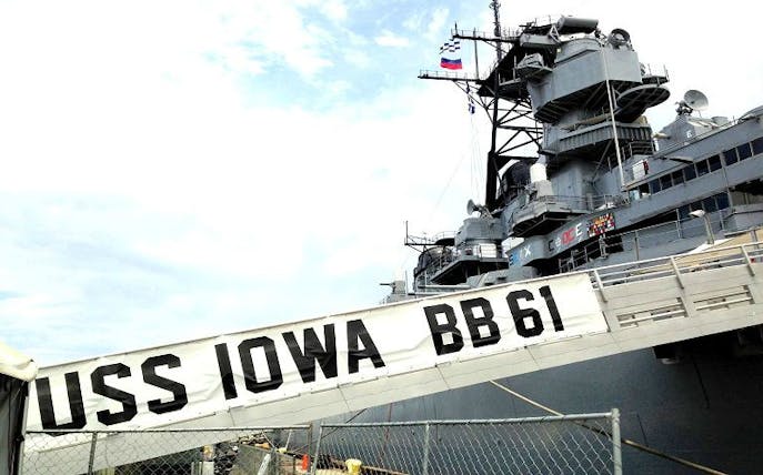 USS Iowa battleship docked in Los Angeles with gangway and flags visible.