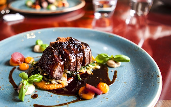 Gourmet dish served on a blue plate during La Marina dinner cruise with champagne.