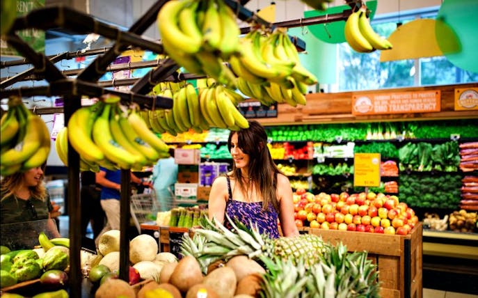 A woman browsing fresh produce at a market during the Seed Food & Wine Festival.