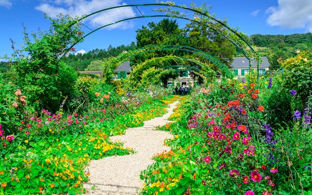 Pathway through vibrant gardens at Giverny, leading to Monet's house, part of Versailles & Giverny tour.