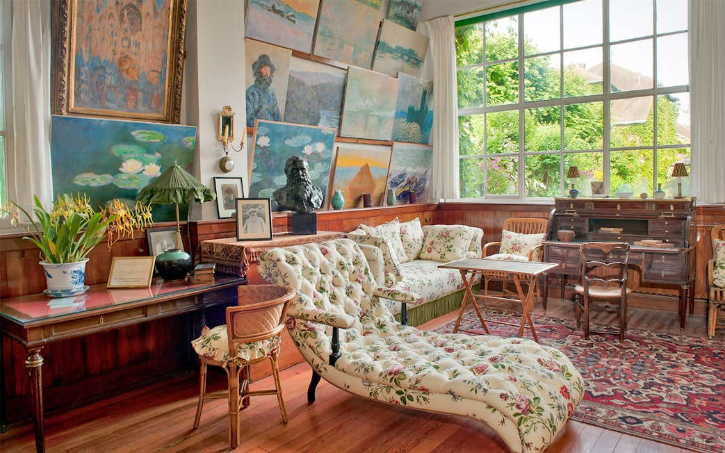 Monet's studio in Giverny with paintings and floral furniture, part of Versailles & Giverny tour.