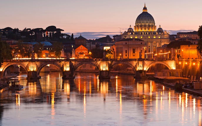 St. Peter's Basilica and Tiber River illuminated at night, Rome bus tour.