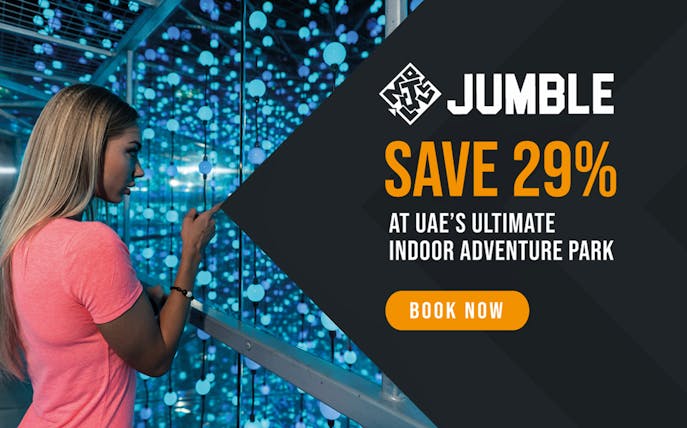 Woman exploring Jumble Dubai's interactive maze with glowing lights.