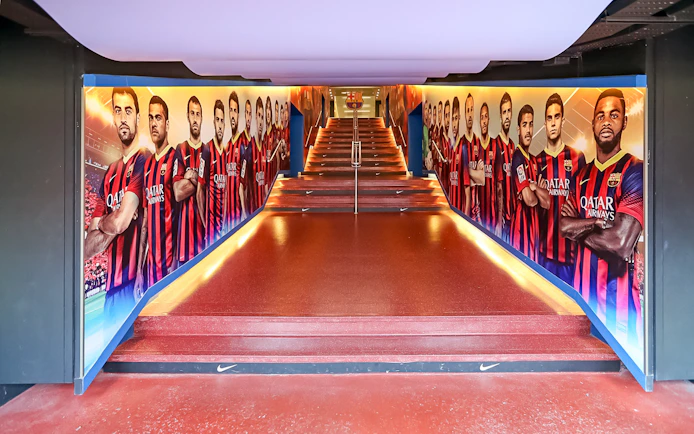 Camp Nou tunnel with FC Barcelona player murals on a guided tour.
