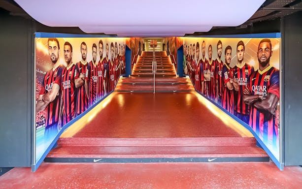 Camp Nou tunnel with FC Barcelona player murals on a guided tour.