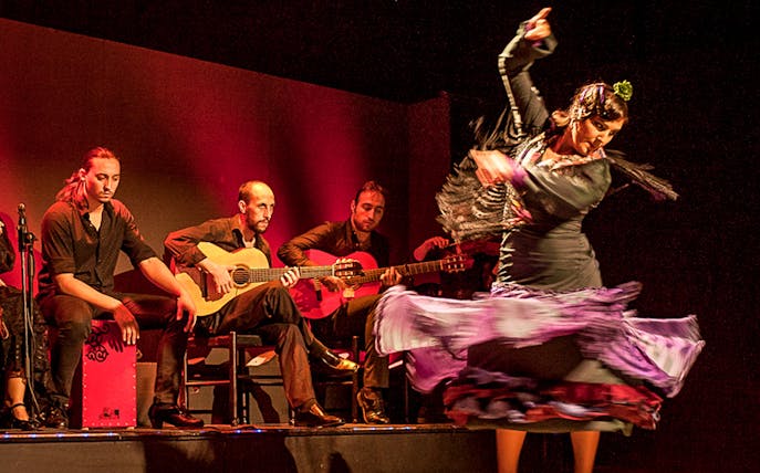 Flamenco dancer performing with musicians on stage in Spain.