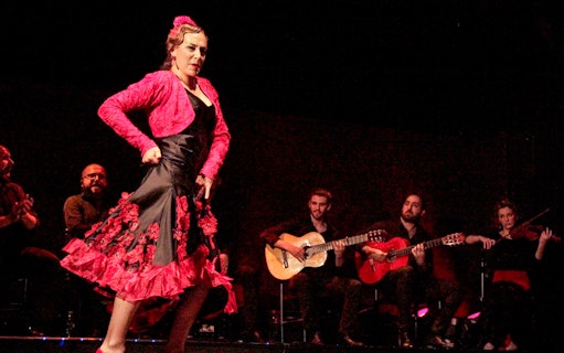 Flamenco dancer performing with musicians on stage in Spain.