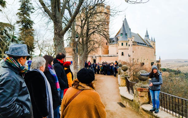 Tour group exploring historic castle in Toledo, Spain, with guide explaining architecture.
