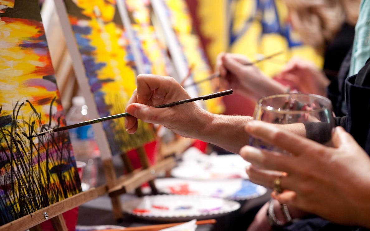 Participants painting on canvases during an Evening Paint and Sip Tour.