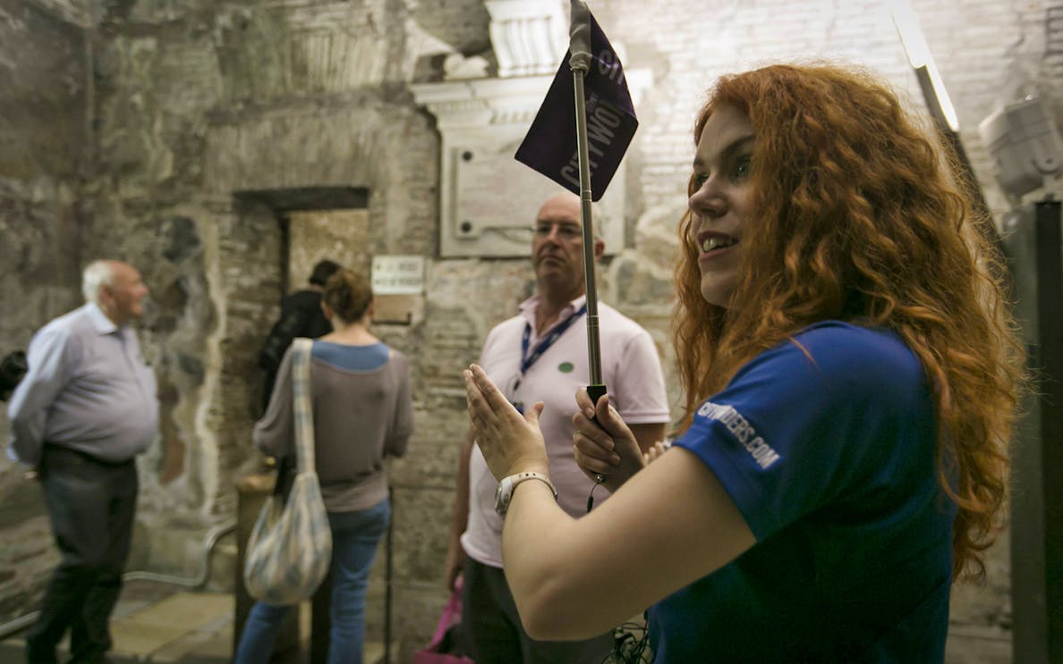 Tour guide leading Crypts and Catacombs tour in Rome with group inside ancient site.