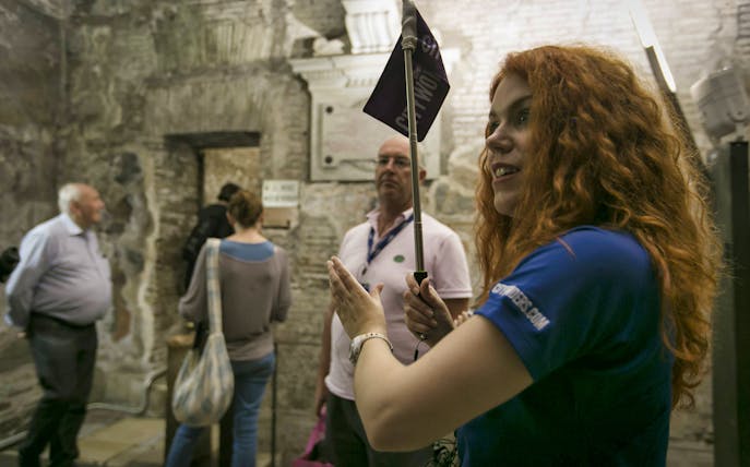 Tour guide leading Crypts and Catacombs tour in Rome with group inside ancient site.