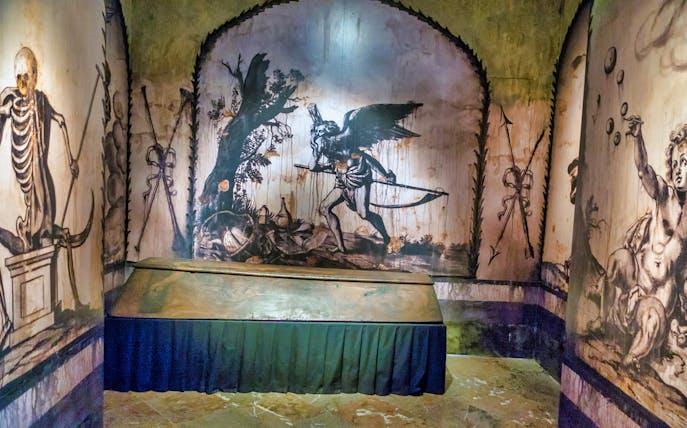 Catacombs of Rome mural with skeletons and scythe, part of exclusive after-hours tour.