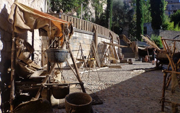 Girona street market set from Game of Thrones with rustic stalls and baskets.