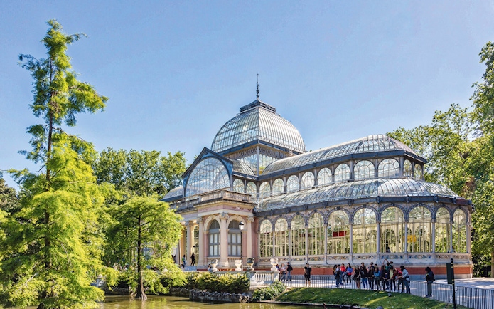 Crystal Palace in El Retiro Park, Madrid, with visitors outside.