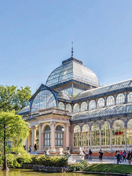 Crystal Palace in El Retiro Park, Madrid, with visitors outside.