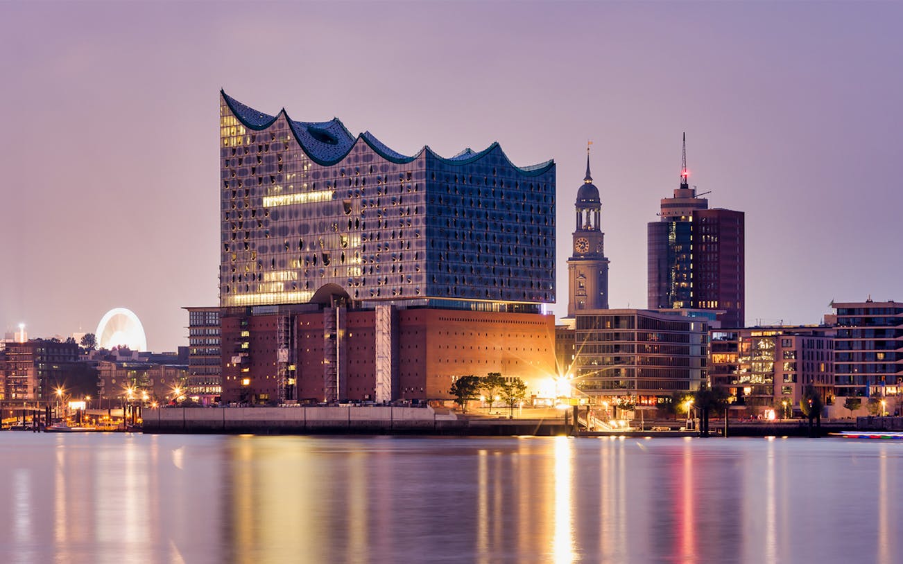 Elbphilharmonie concert hall illuminated at dusk, Hamburg harbor view.