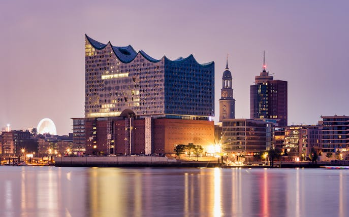 Elbphilharmonie concert hall illuminated at dusk, Hamburg harbor view.