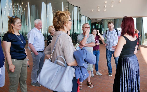 Group listening to a guide at Elbphilharmonie during Hamburg harbor tour.