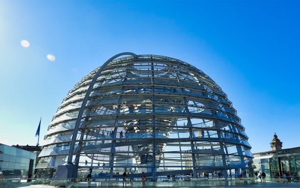 Reichstag dome in Berlin under clear blue sky.