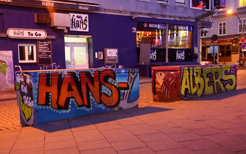 Graffiti art on barriers outside a bar in Hamburg's Reeperbahn district at night.