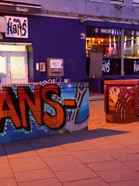 Graffiti art on barriers outside a bar in Hamburg's Reeperbahn district at night.