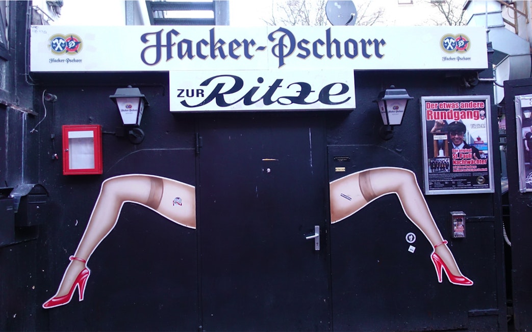 Entrance to Zur Ritze bar in Hamburg's Reeperbahn, featuring iconic leg artwork.
