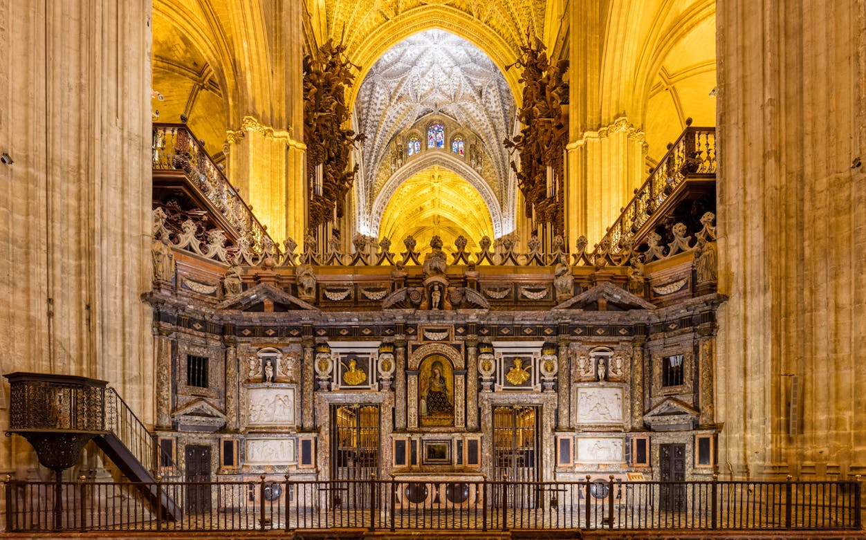 Cathedral interior with ornate altar and vaulted ceiling, part of Skip the Line Guided Tour to Cathedral & Giralda Towers.