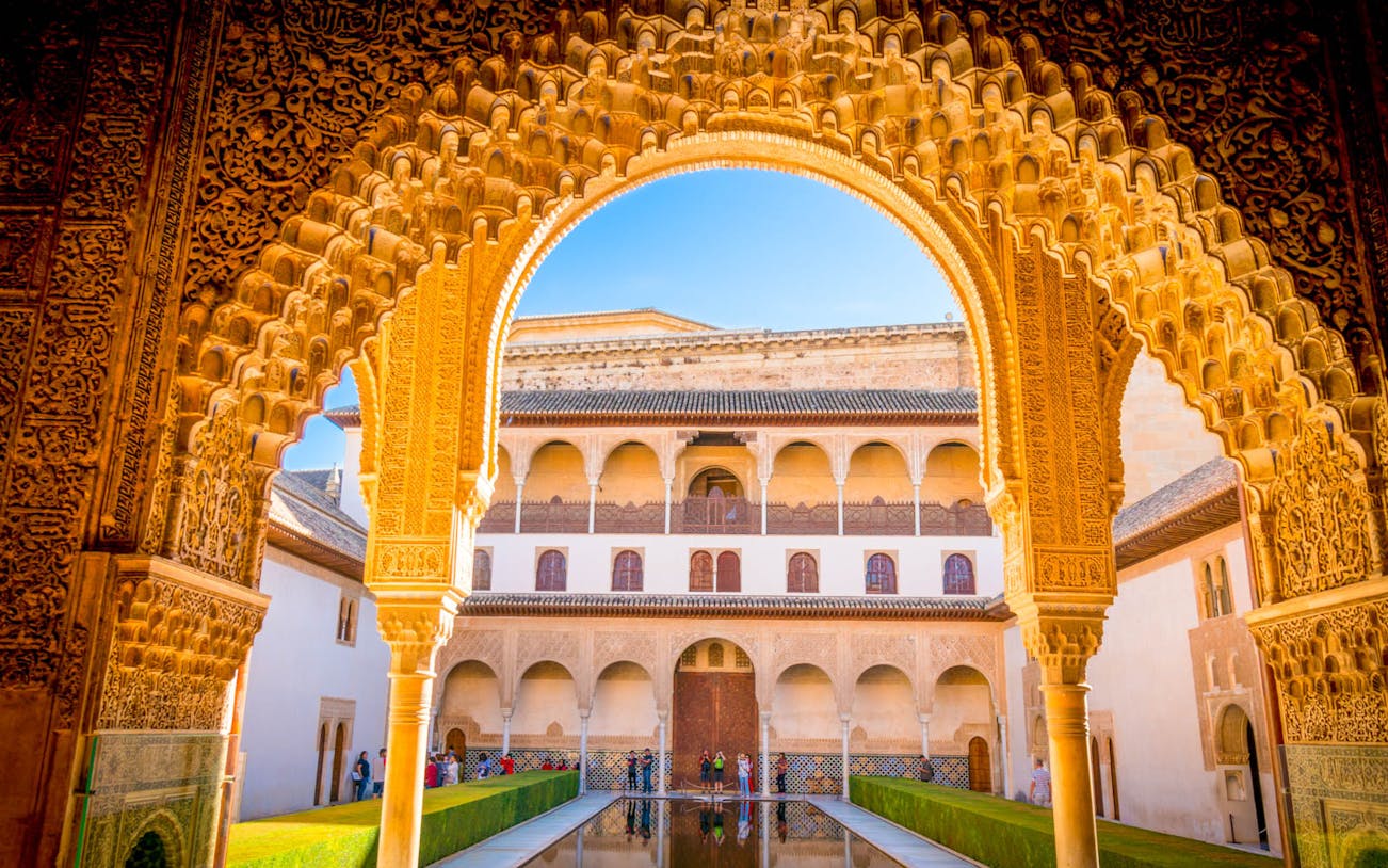 Alhambra's intricate archway framing the courtyard and reflecting pool, Granada, Spain.