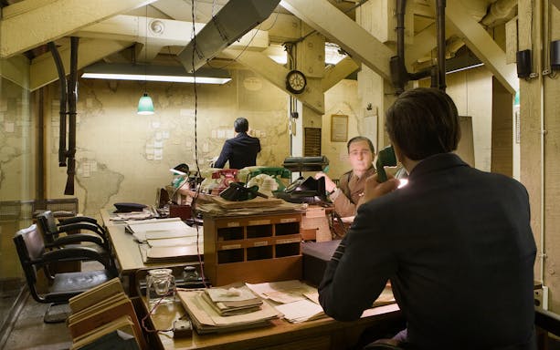 War Room scene at Churchill War Rooms, London, with figures at desks and a large map on the wall.