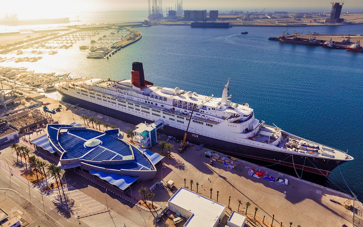 Queen Elizabeth 2 docked at Port Rashid, Dubai, with surrounding marina.