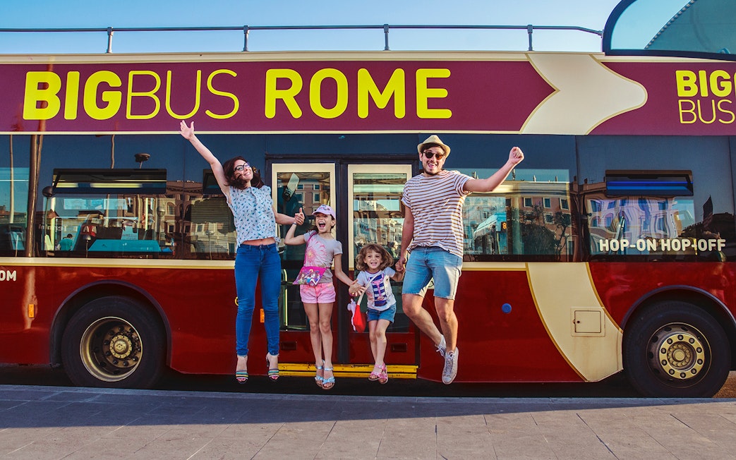 Family jumping in front of a Big Bus Rome tour bus, enjoying a hop-on hop-off experience.