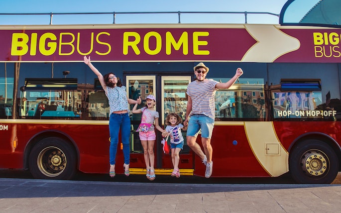 Family jumping in front of a Big Bus Rome tour bus, enjoying a hop-on hop-off experience.