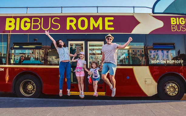 Family jumping in front of a Big Bus Rome tour bus, enjoying a hop-on hop-off experience.