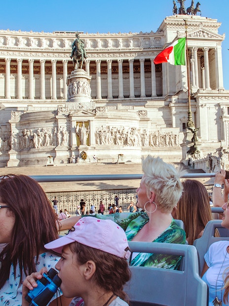 Tourists on a hop-on hop-off bus viewing the Altare della Patria in Rome.