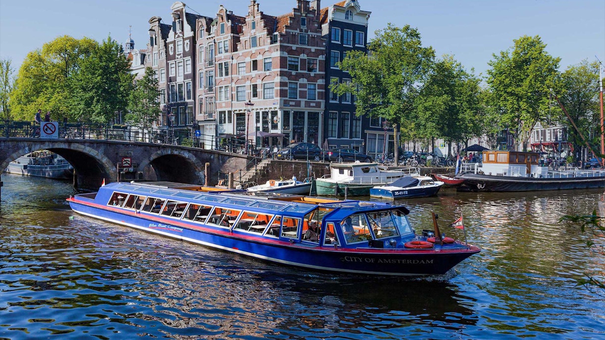 Canal boat cruising past historic buildings in Amsterdam.